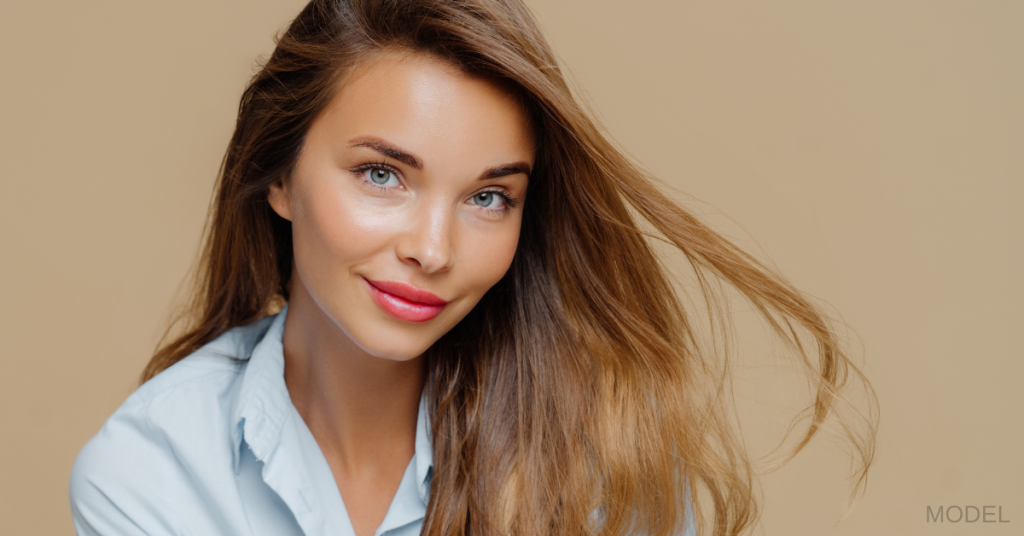 Beautiful woman in a blue shirt smiling with long hair blowing (model)