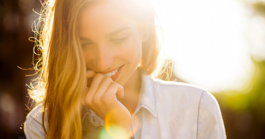 Woman smiling with sun behind her