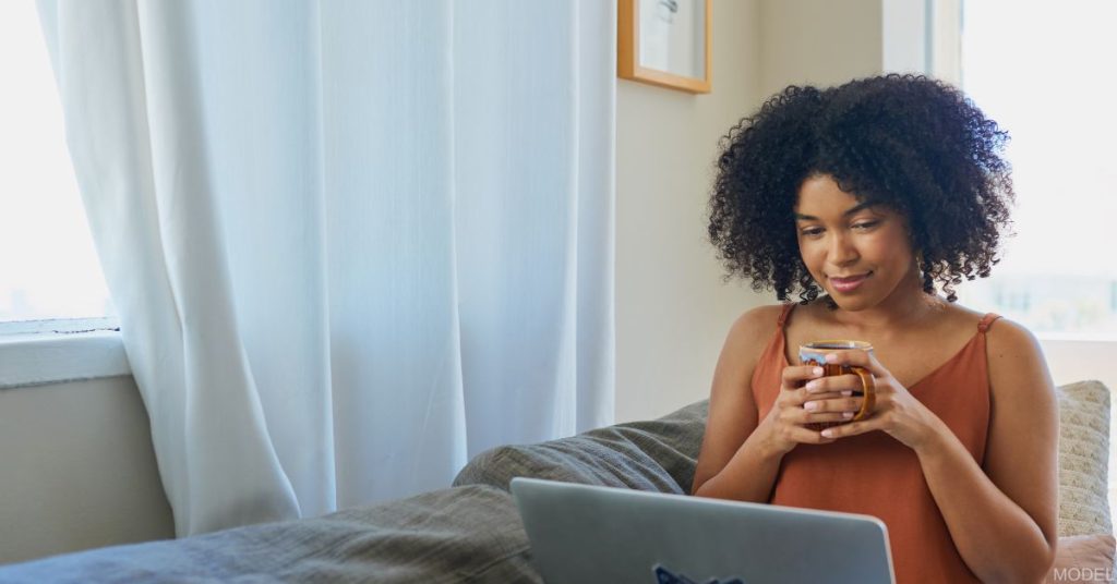 Woman sitting on a couch looking at a computer (model)