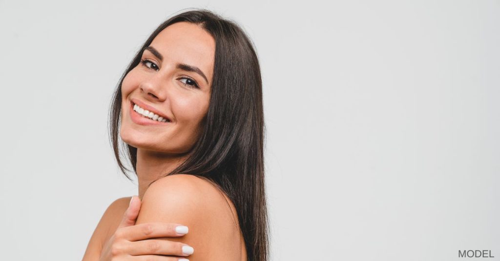 Brunette woman (model) with clear skin smiling.