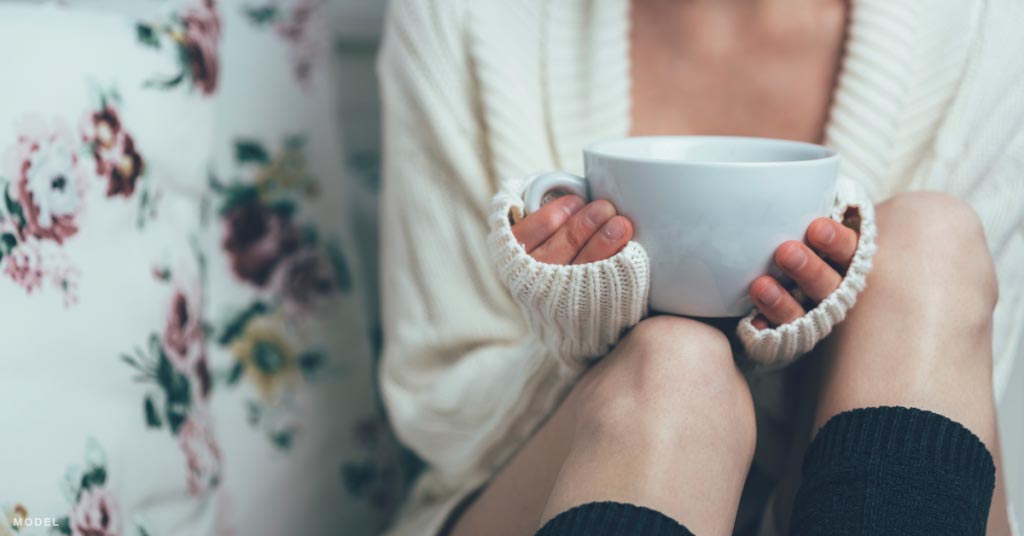 A woman holding a tea mug over smooth legs