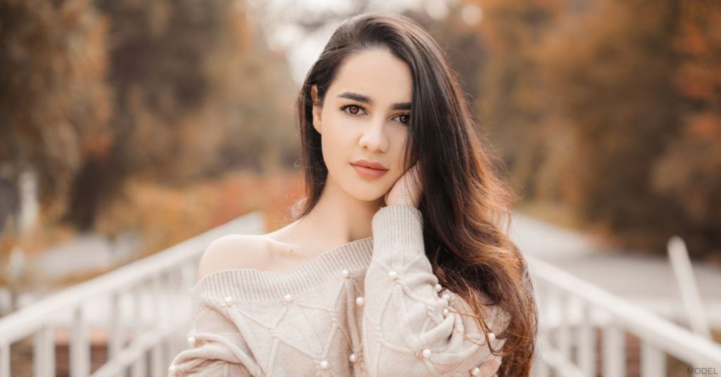 Woman touching her face in front of autumn background (model)